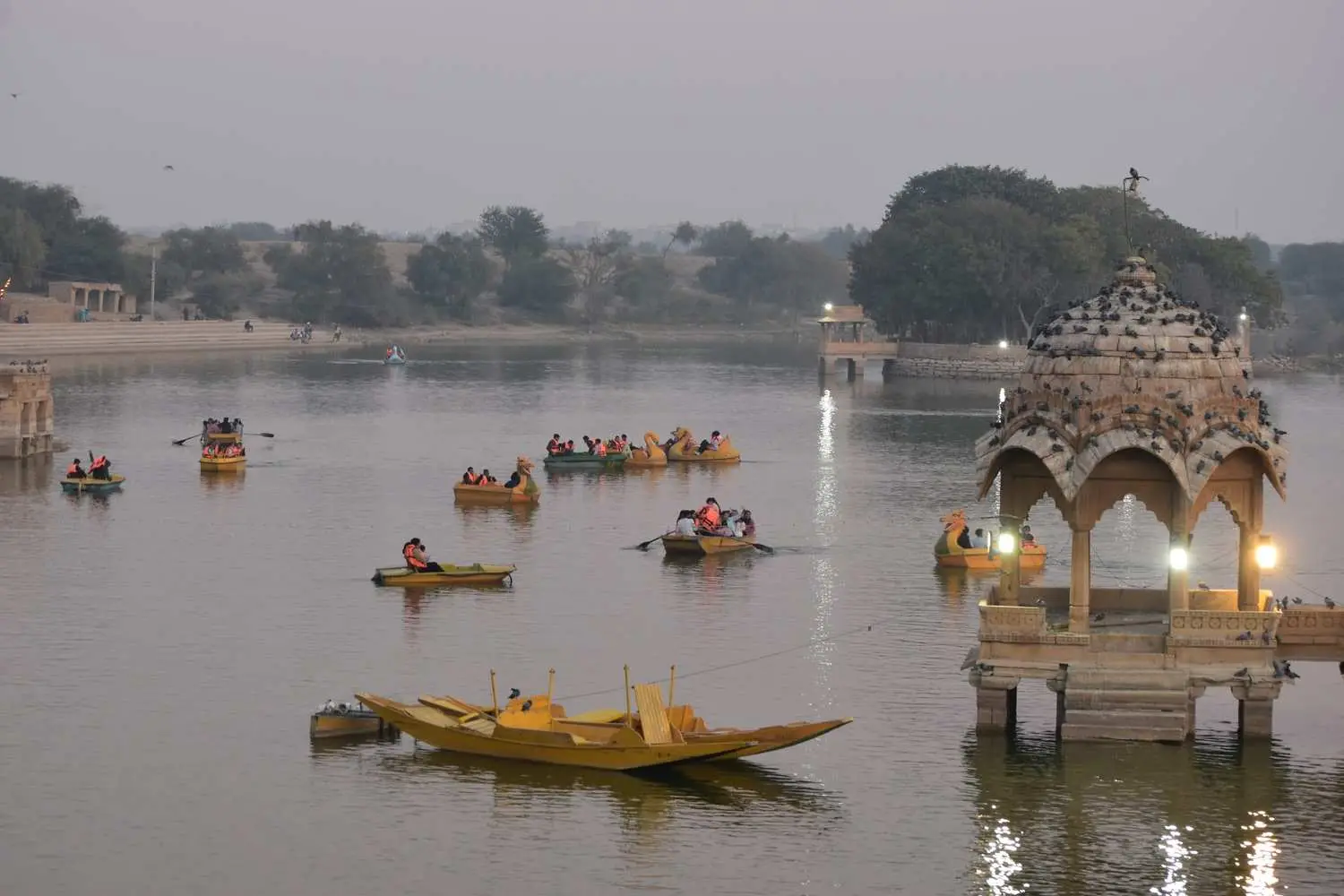 Boats on a calm lake beside carved sandstone pavilions